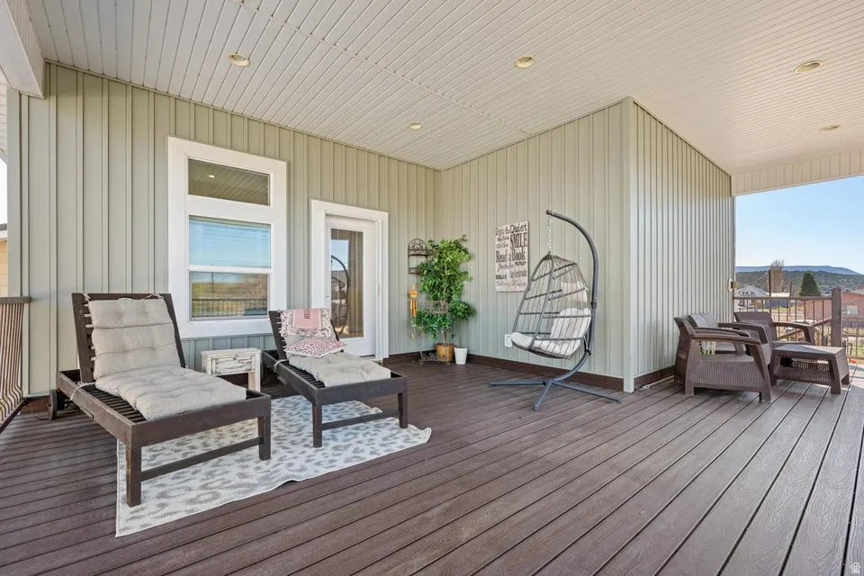Expansive covered deck featuring composite decking, vertical panel siding, and a white paneled ceiling with recessed lighting
