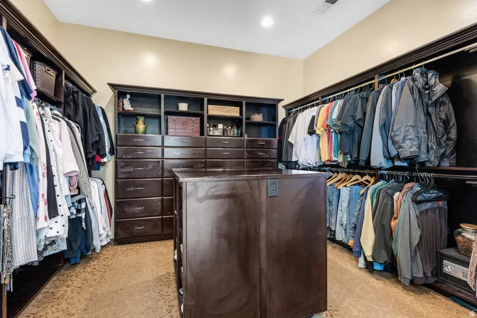 Custom built-in dark wood cabinetry, extensive shelving, multiple drawer banks, and a central island with built-in outlets