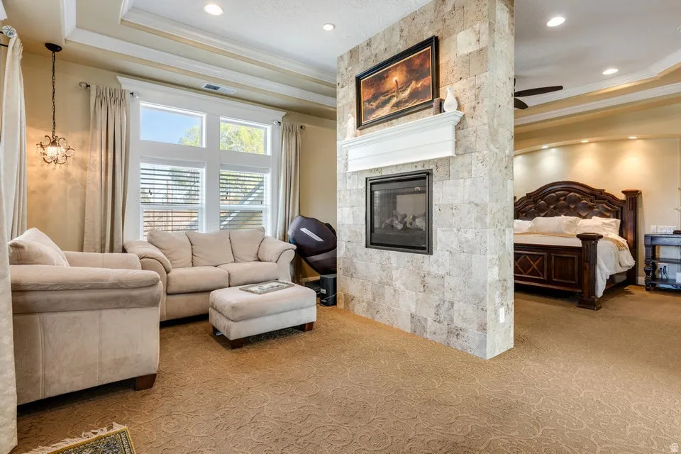 Recessed lighting, tray ceiling, tiled fireplace with mantel, and large windows