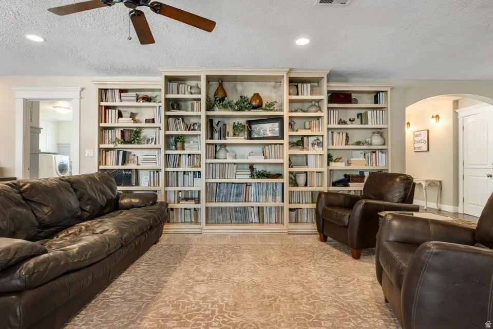 Built-in shelving units, recessed lighting, and a ceiling fan with wood-finish blades