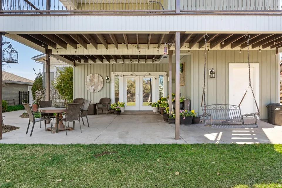 Covered concrete patio with a full-light French door entry and exterior lighting