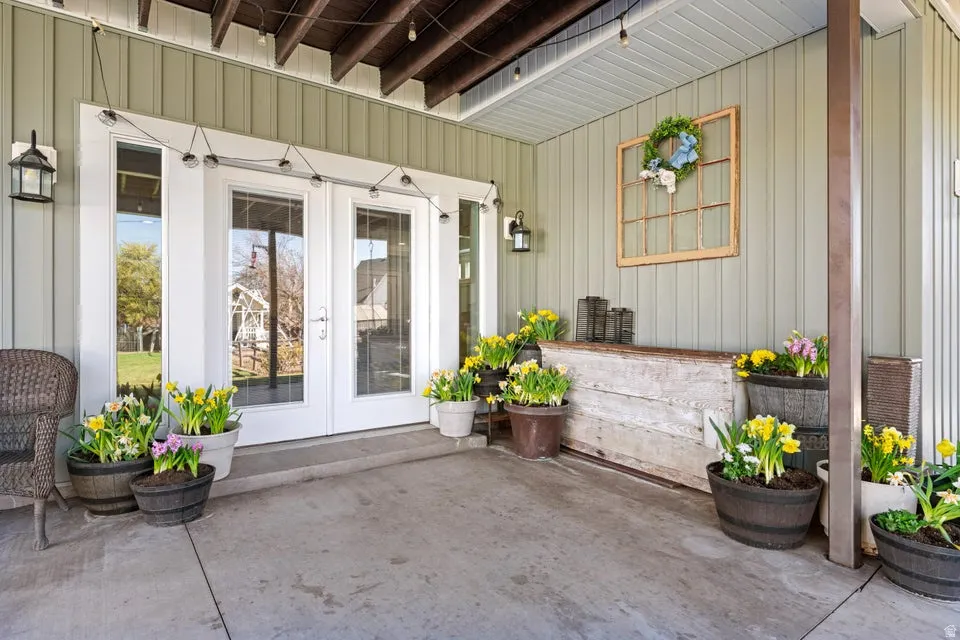 Concrete patio with white French doors, vertical siding, and exposed ceiling joists