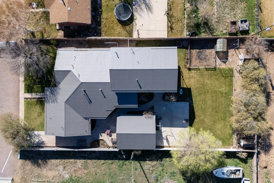 Expansive property featuring a multi-level metal roof, concrete patio, and a grass lawn