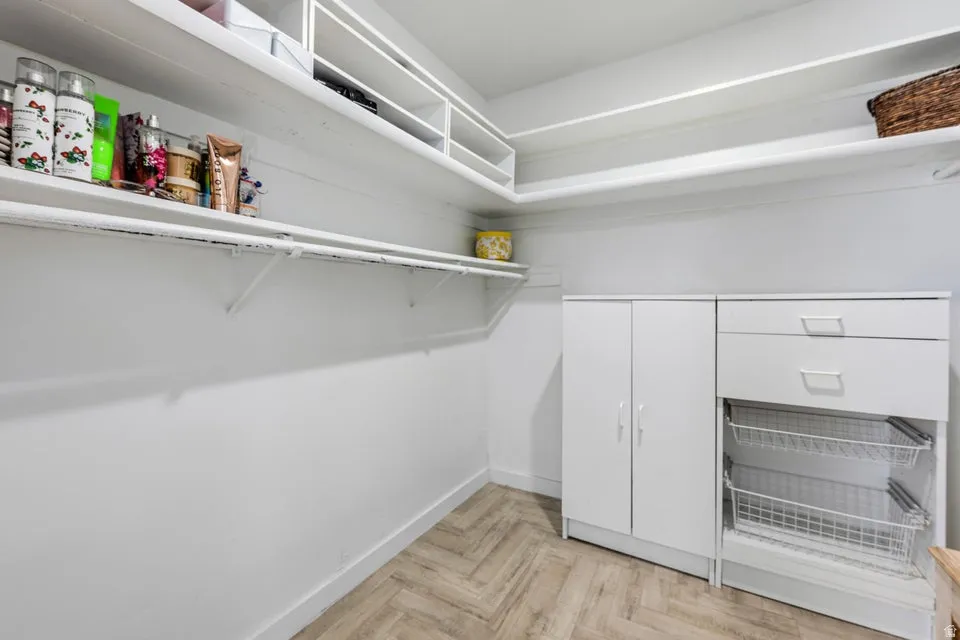 Built-in shelving, wood-finish flooring, white cabinetry, integrated drawers, and wire pull-out baskets