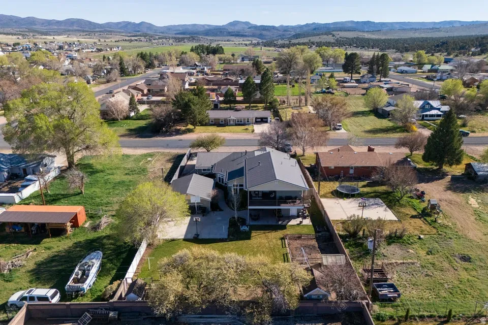 Two-story residence with a gray shingle roof, featuring a covered upper-level deck and a concrete patio