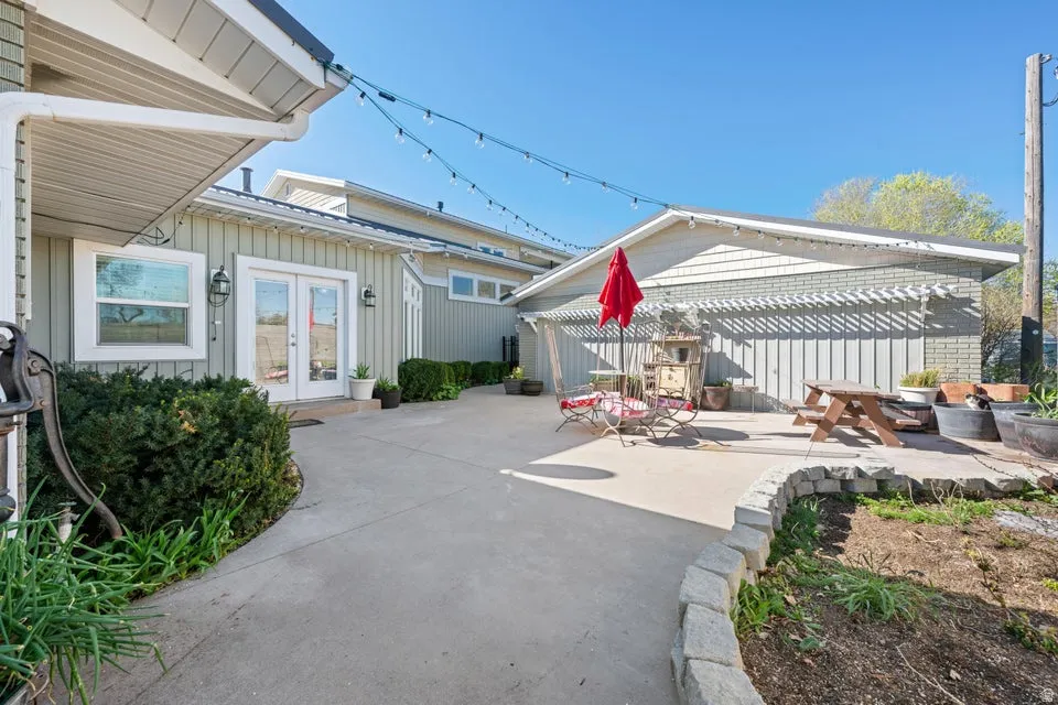 Concrete patio with a decorative pergola and stone retaining wall