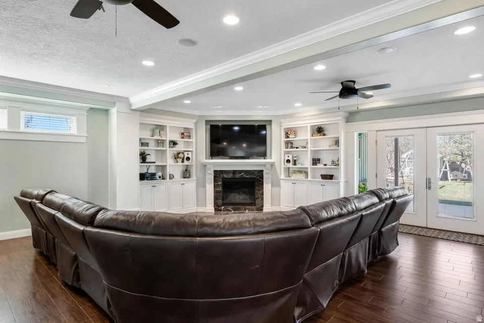 Built-in cabinetry flanking a corner fireplace, recessed lighting, ceiling fans, and wood-finish flooring