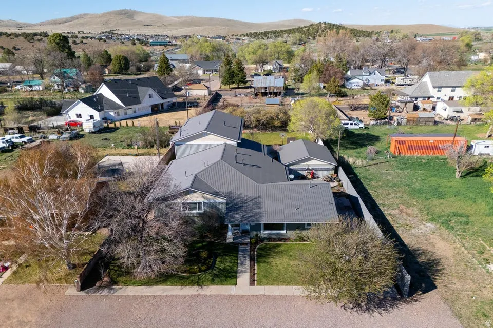 Property featuring a dark metal roof, light-colored siding, attached garage, and a green front lawn