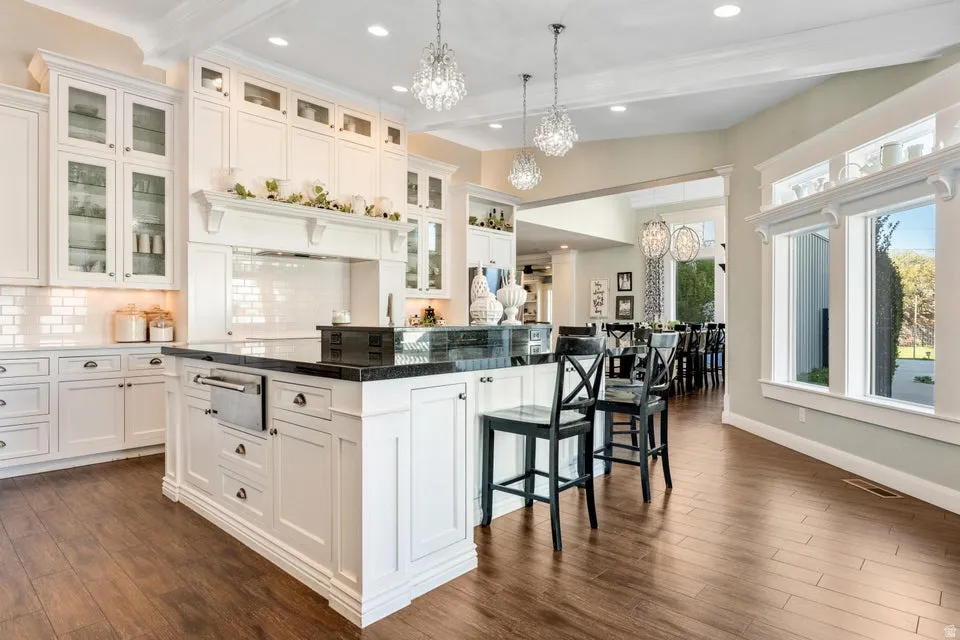 Bright kitchen featuring white cabinetry, dark countertops, wood-finish flooring, and recessed lighting