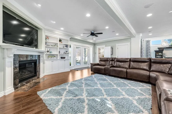 Fireplace with a stone surround, built-in shelving, wood-finish flooring, recessed lighting, and French doors