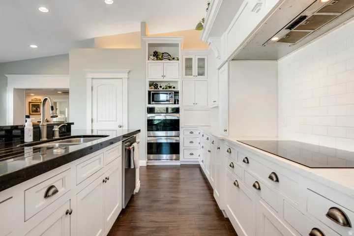 Kitchen featuring extensive white cabinetry, dark wood-finish flooring, recessed lighting, and a white subway tile backsplash