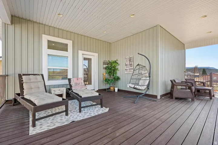 Expansive covered deck featuring composite decking, vertical panel siding, and a white paneled ceiling with recessed lighting