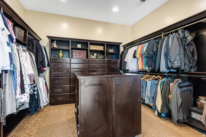 Custom built-in dark wood cabinetry, extensive shelving, multiple drawer banks, and a central island with built-in outlets