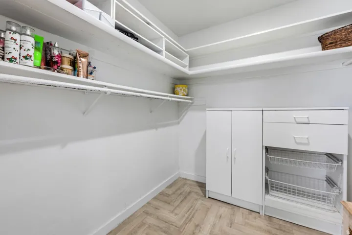 Built-in shelving, wood-finish flooring, white cabinetry, integrated drawers, and wire pull-out baskets