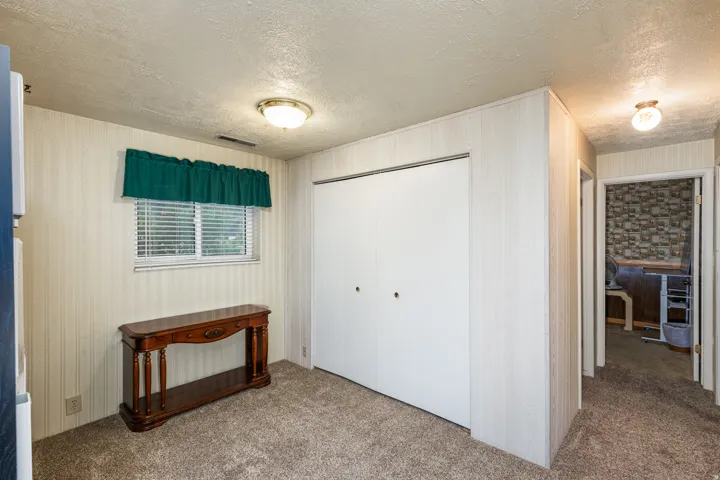 Carpeted room with a window, white blinds, and a flush-mount light fixture
