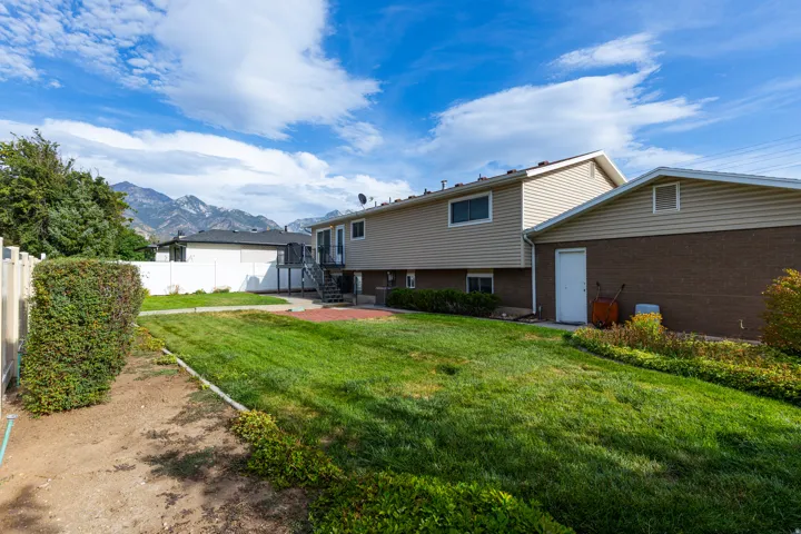 Spacious backyard with mature landscaping, established lawn, and mountain backdrop