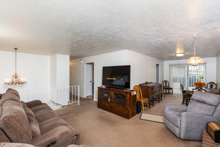 Spacious living area featuring textured ceiling detail, wood-finish entertainment cabinetry with integrated fireplace, pendant lighting fixtures, and plush seating arrangements throughout