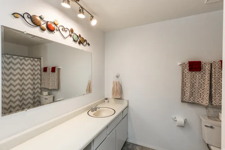 Spa-inspired bathroom featuring a generous vanity with dual-sink configuration, expansive mirror with integrated lighting, and tile flooring