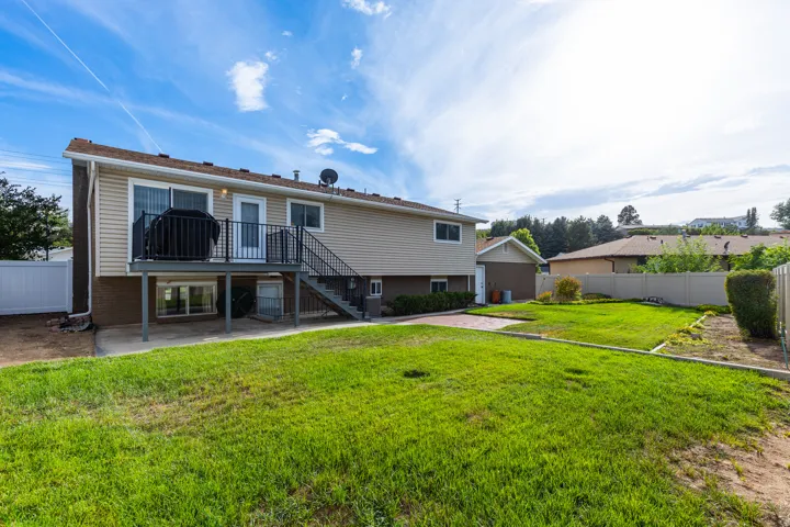 Expansive grass yard with a white privacy fence