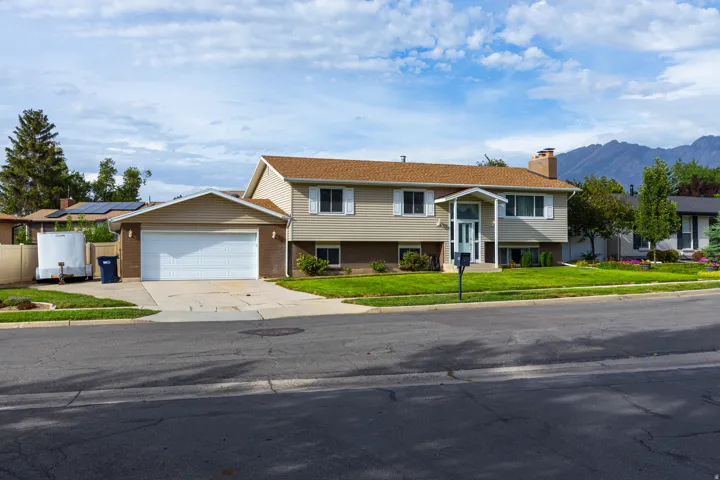 Two-story residence featuring a composed facade with mixed siding materials, a front-facing garage with white paneled doors, and a covered entry portico