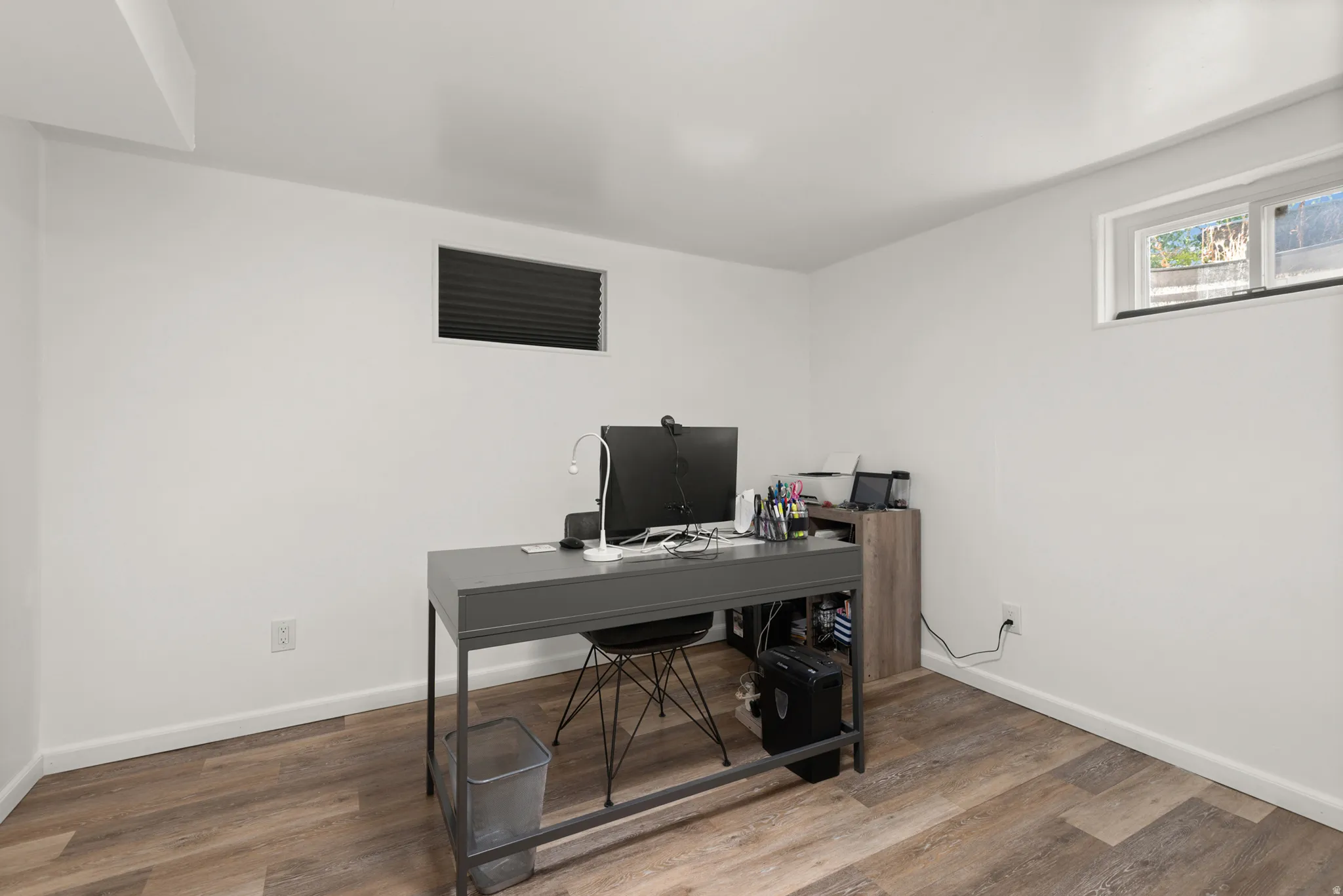 Room featuring wood-finish flooring, two windows, and white painted walls