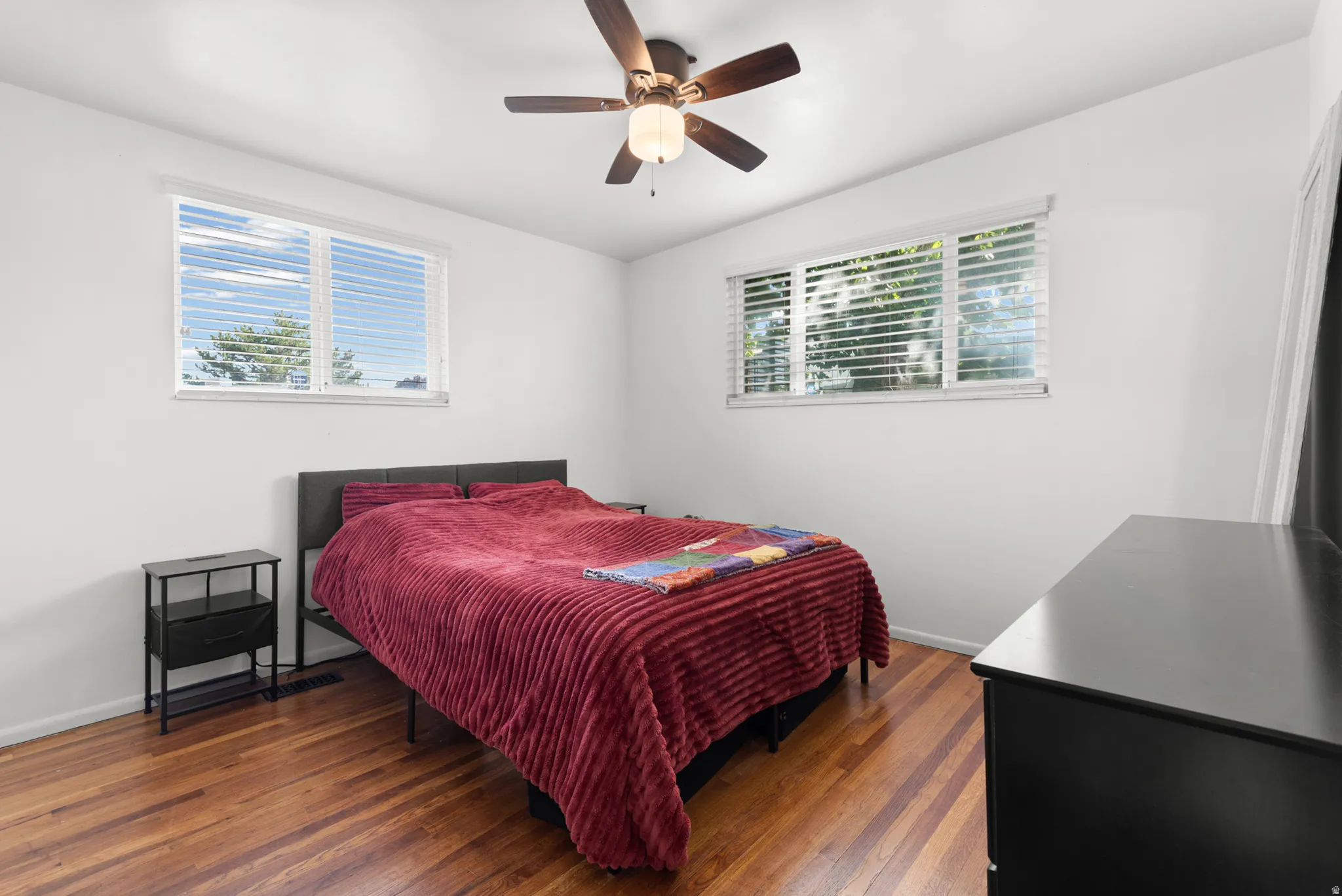 Hardwood flooring, white walls, and a ceiling fan with integrated lighting