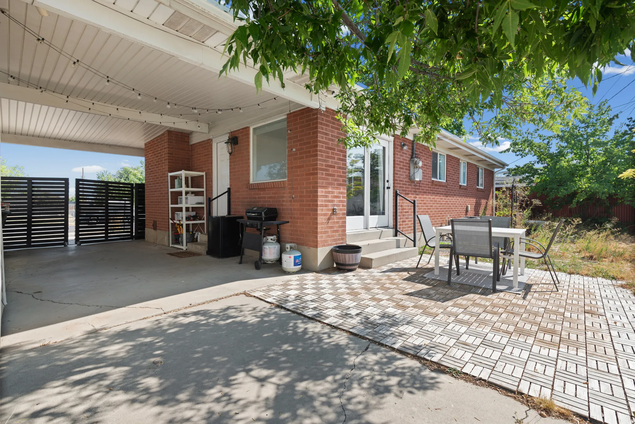 Covered patio with a concrete floor, brick exterior, and a slatted privacy fence