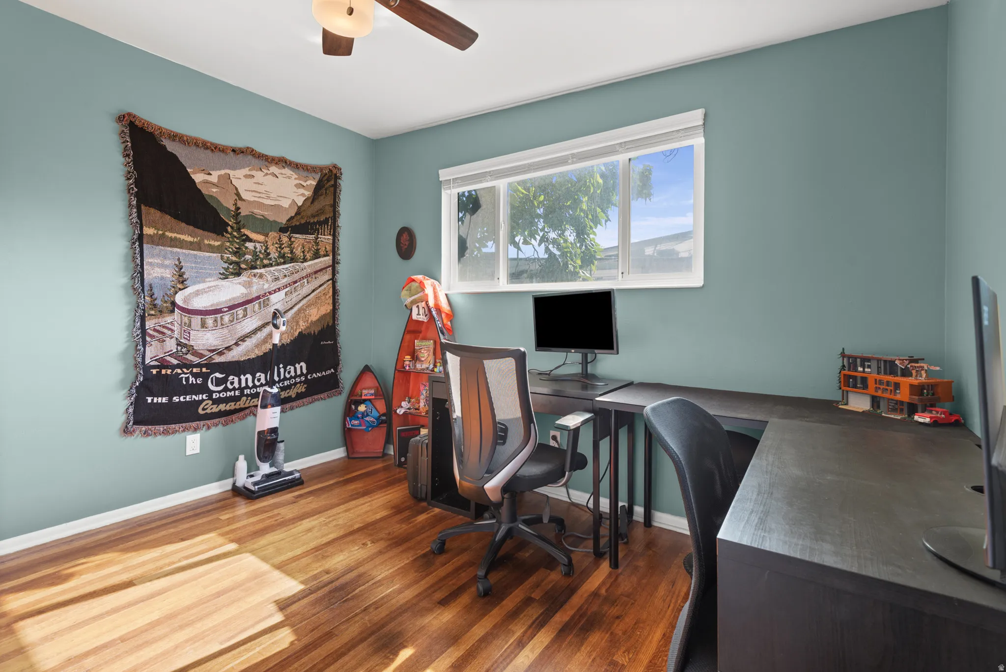 Room featuring wood-finish flooring, a ceiling fan with integrated lighting, and a large window