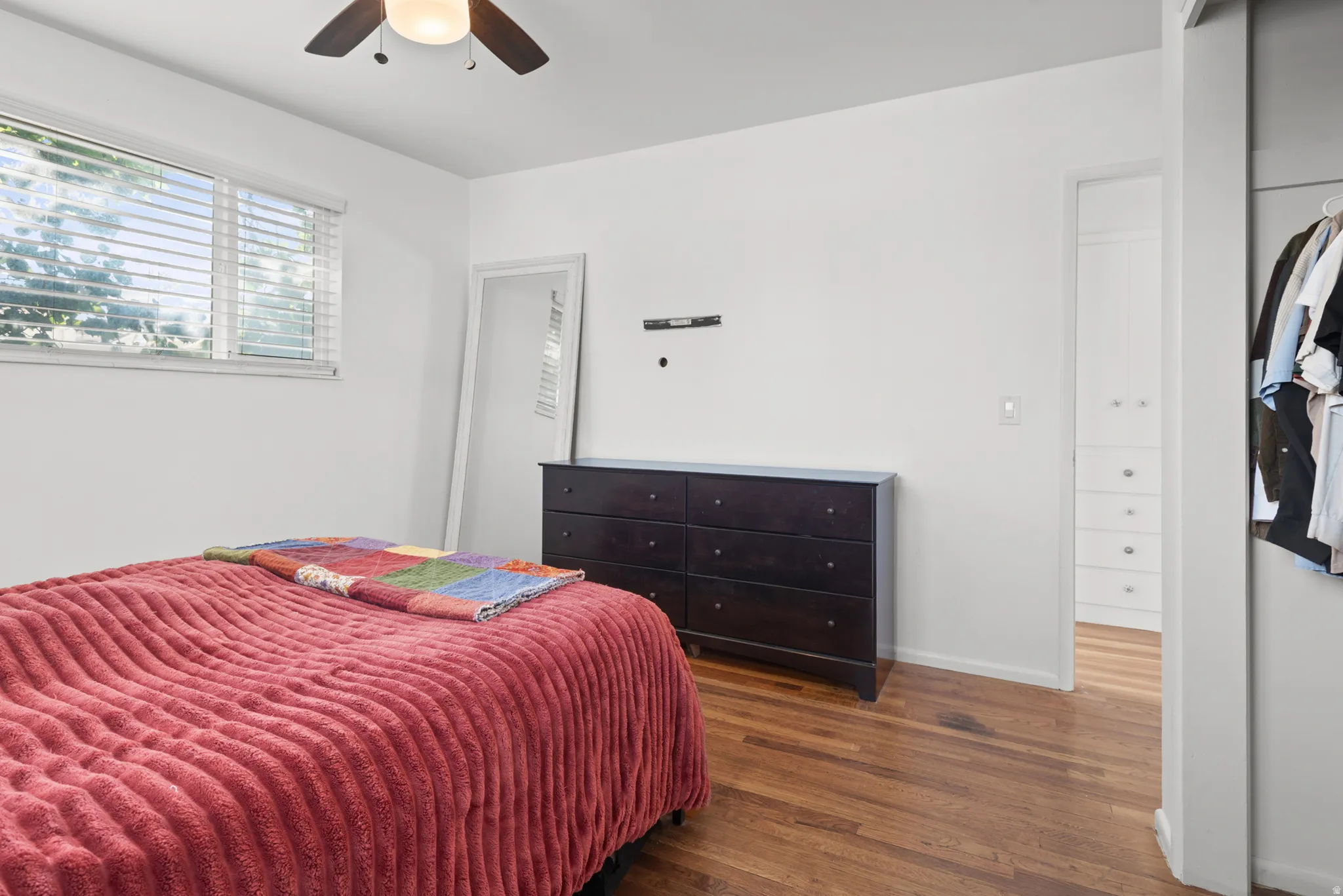 Hardwood flooring, window with horizontal blinds, ceiling fan with integrated lighting, and a built-in closet with shelving