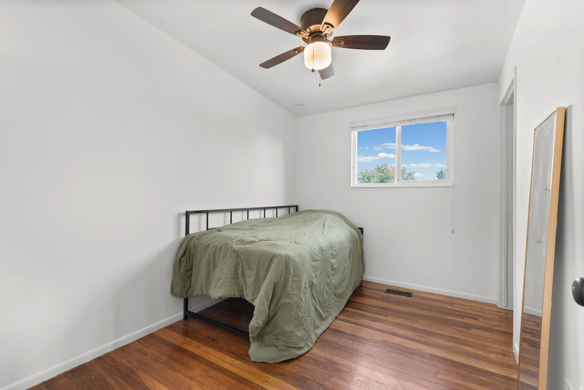 Wood-finish flooring with a ceiling fan light fixture and a window