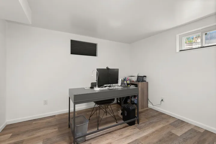 Room featuring wood-finish flooring, two windows, and white painted walls