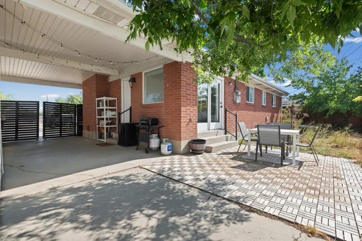 Covered patio with a concrete floor, brick exterior, and a slatted privacy fence