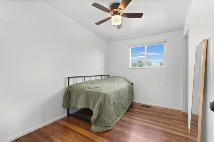 Wood-finish flooring with a ceiling fan light fixture and a window