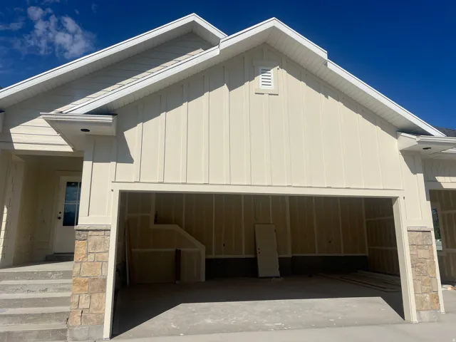 Board and batten siding with stone accents, concrete driveway, and an attached garage with interior staircase