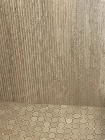 Textured wall tile paired with circular mosaic floor tiling