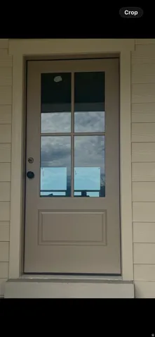Entry door with six-lite window panels, a raised panel lower section, and dark-finish hardware