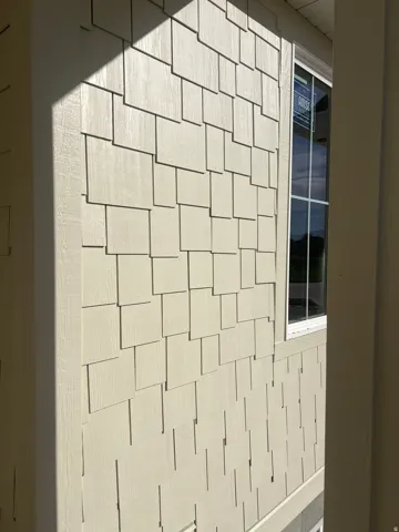 Decorative staggered-edge shingle siding with a smooth finish, framed by vertical trim