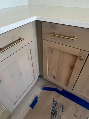 Light-toned wood cabinetry with brass hardware and light-colored countertops