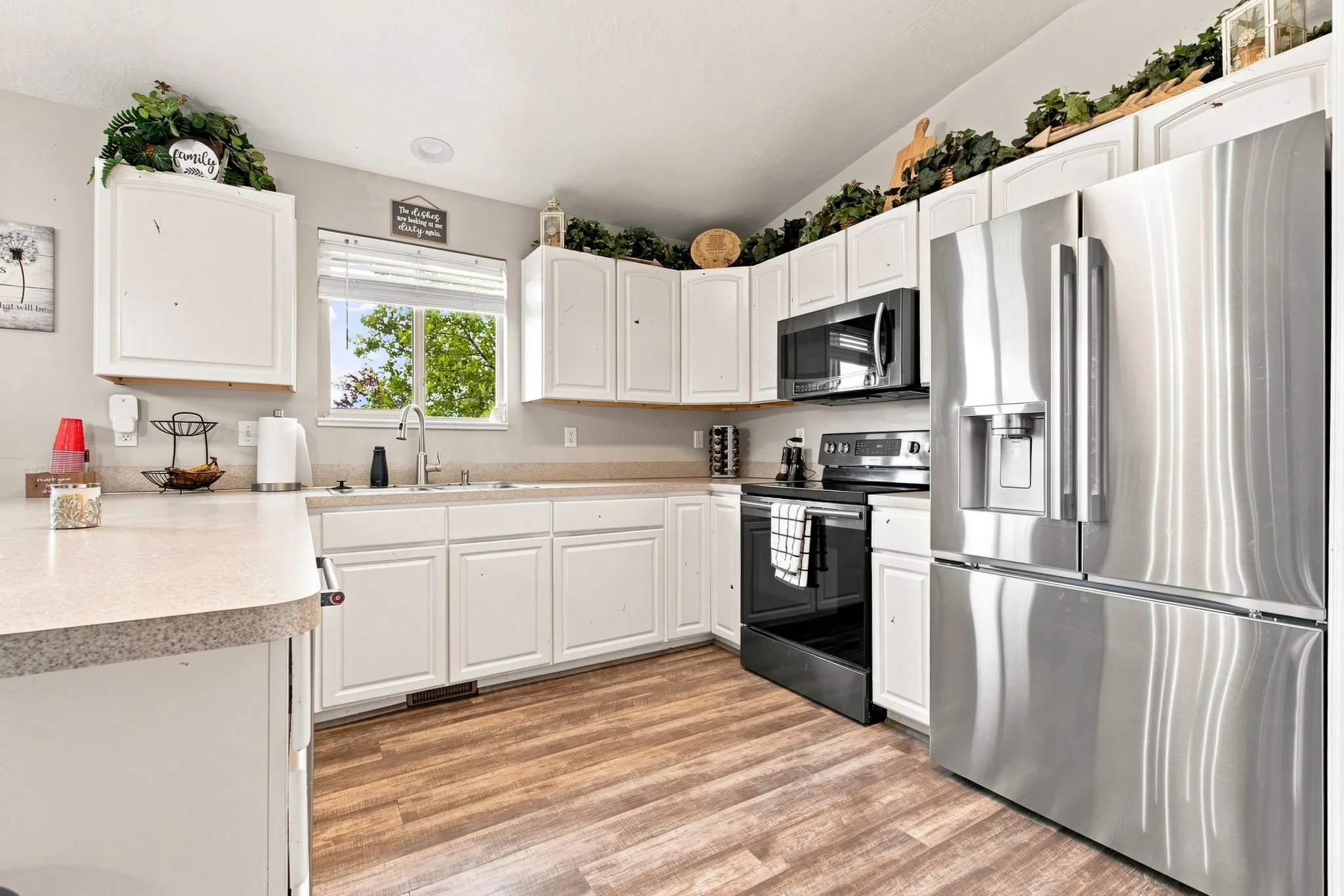 Kitchen featuring wood-finish flooring, white cabinetry, a stainless steel refrigerator, and a black range