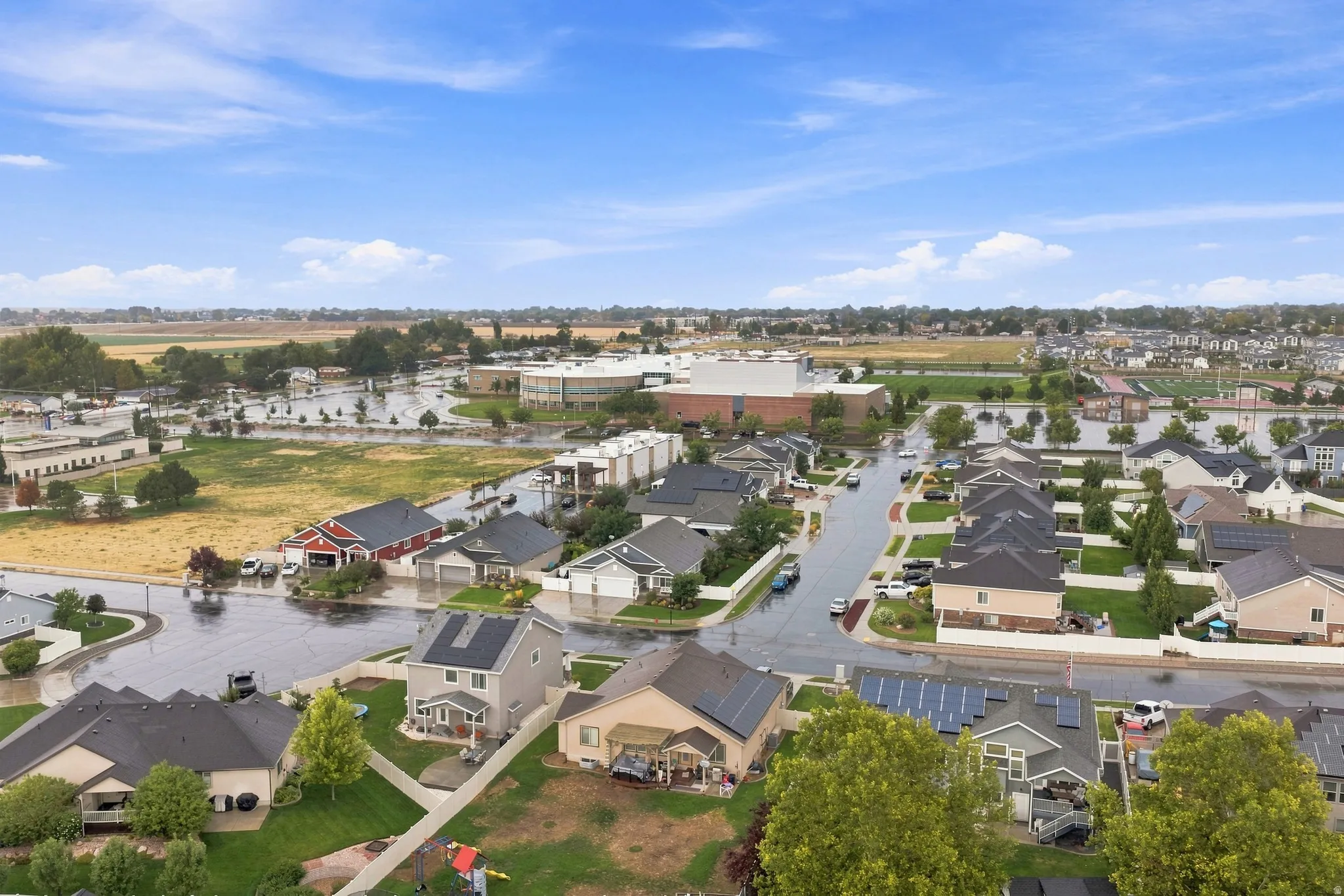 Residential neighborhood with multiple properties featuring solar panels, paved streets, and landscaped yards