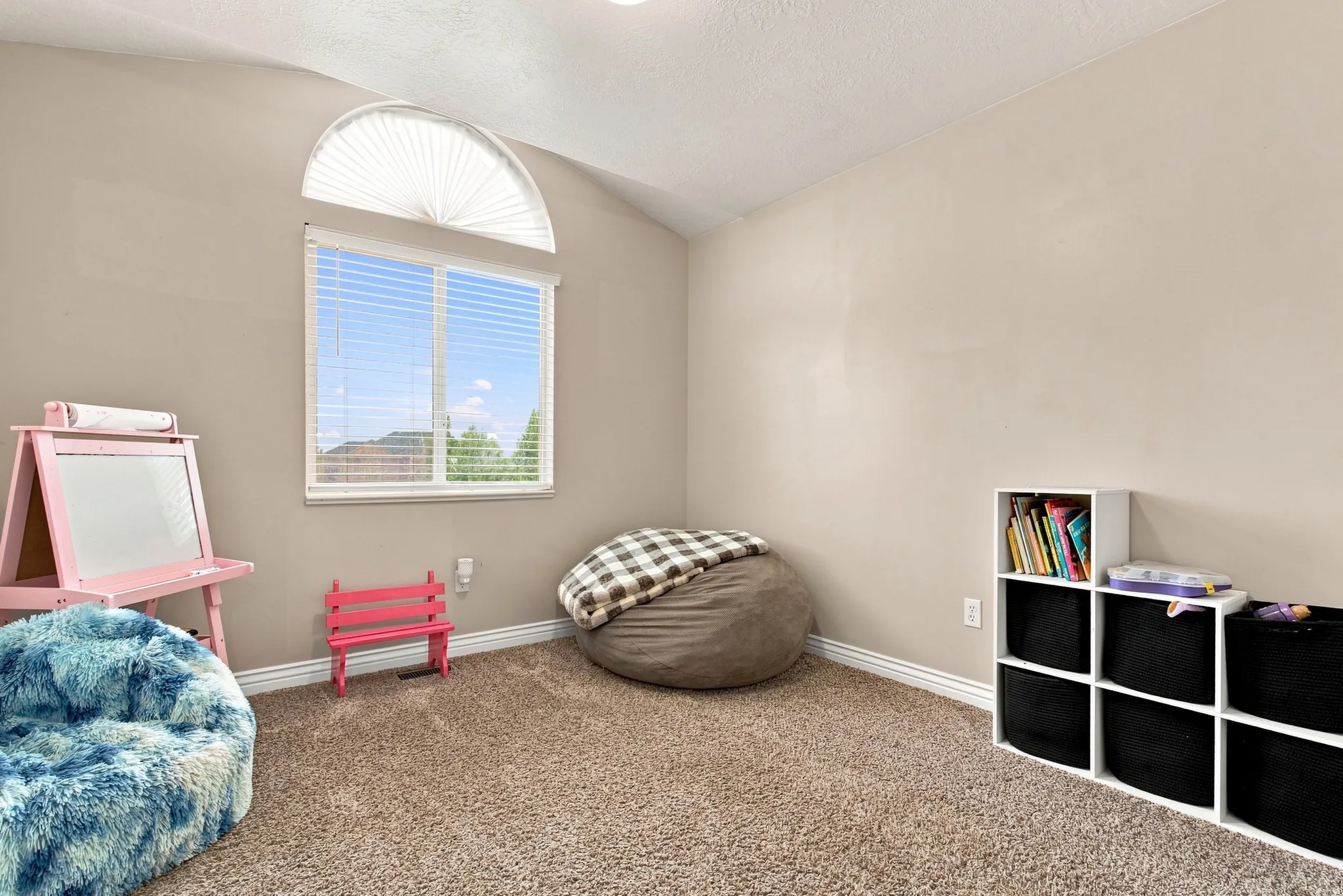 Vaulted ceiling with an arched window, white window blinds, and neutral wall paint