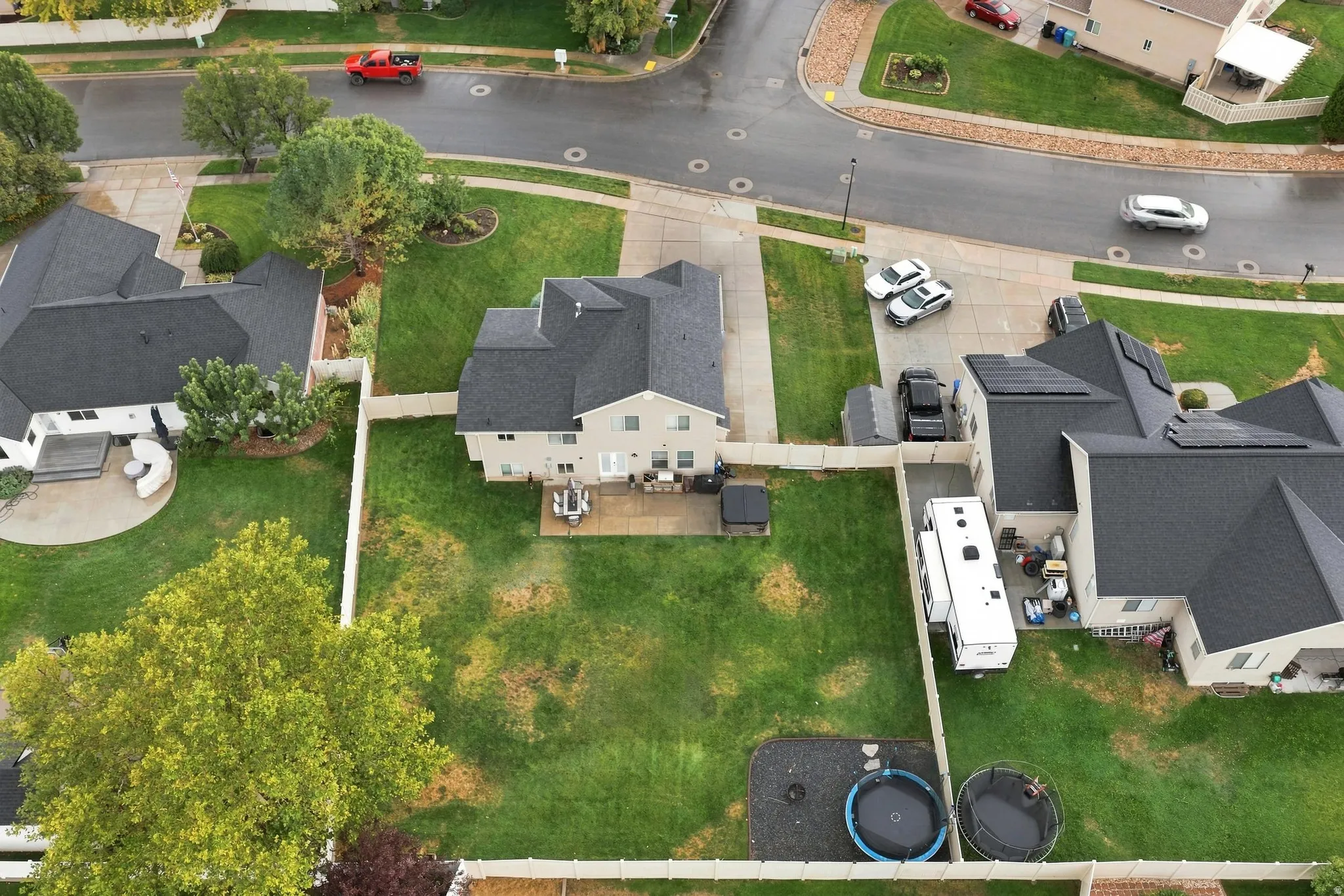 Expansive rear yard with a paved patio, mature trees, and fencing