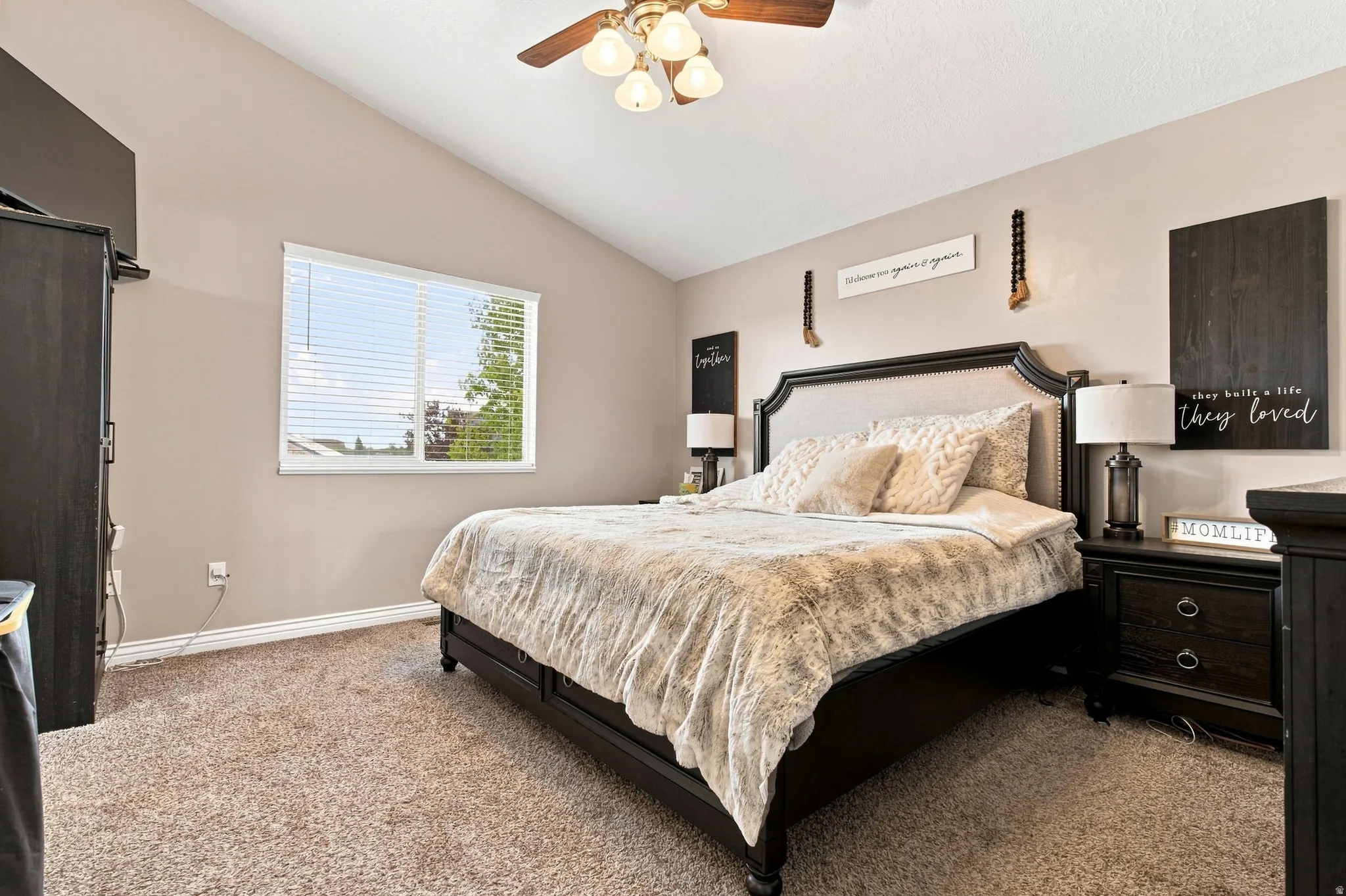 Vaulted ceiling, ceiling fan, natural light from a window with blinds, and neutral carpet flooring