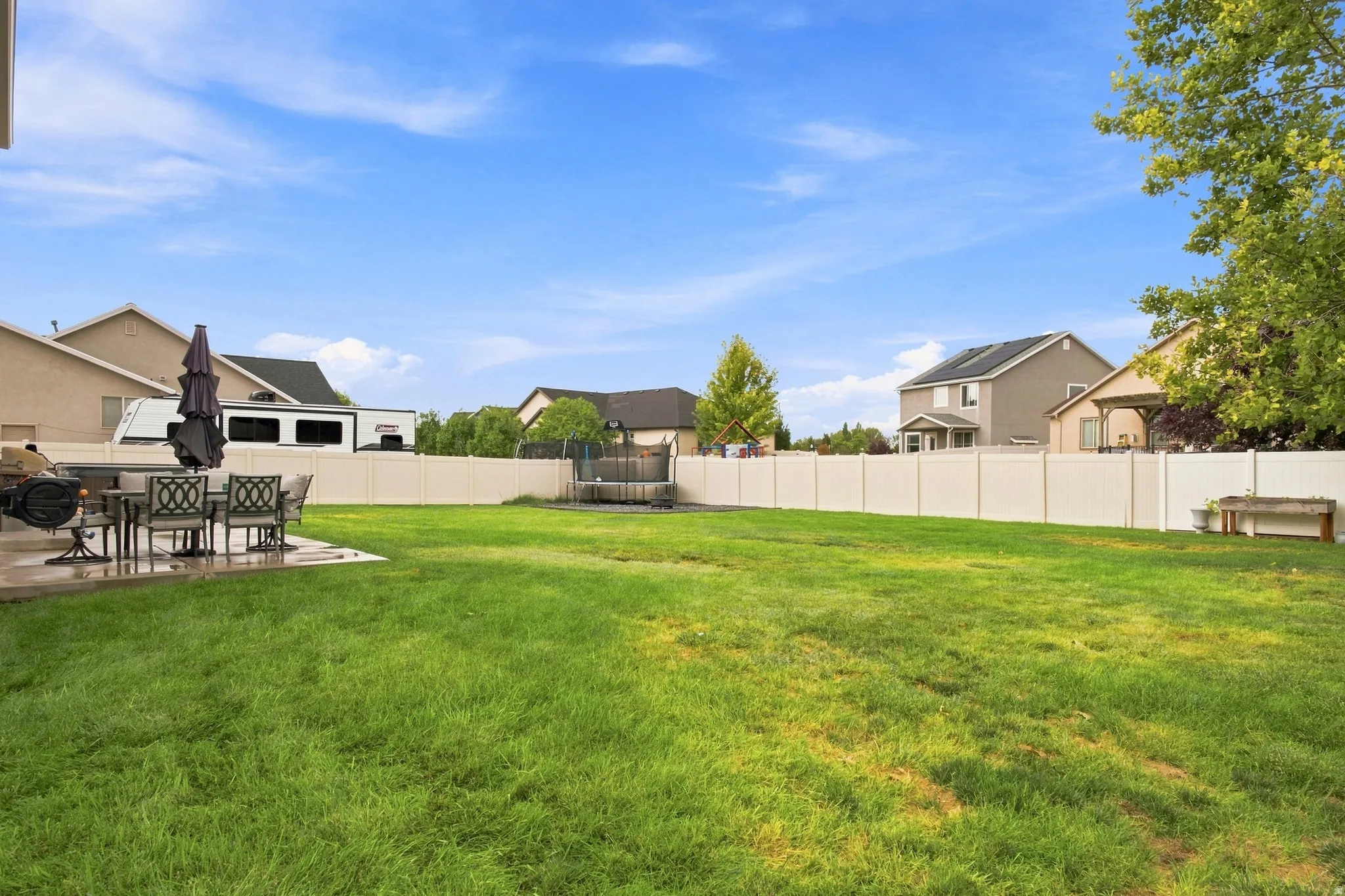 Expansive backyard featuring a lush lawn, concrete patio, and privacy fencing