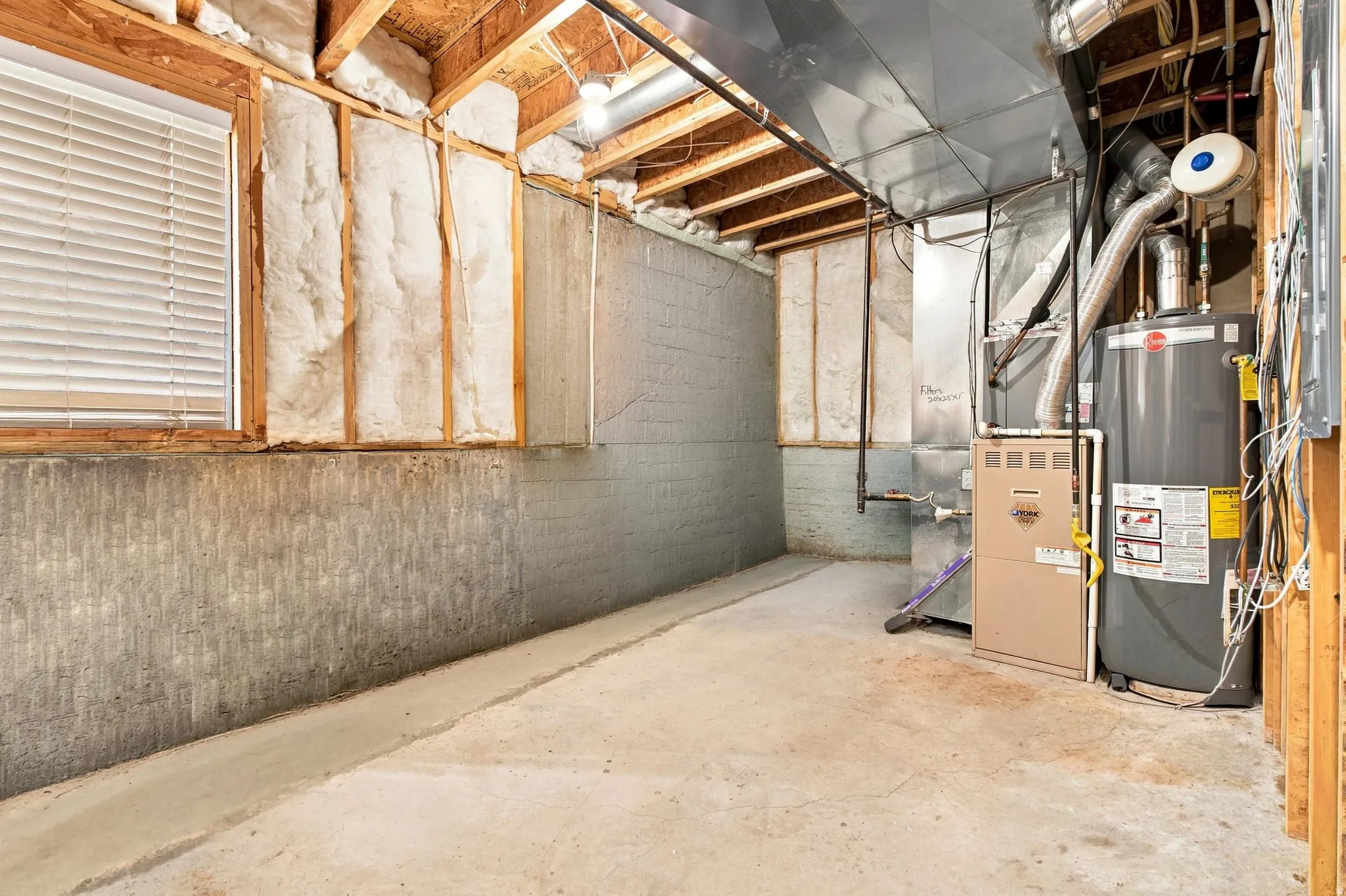 Unfinished basement with exposed ceiling joists, concrete foundation walls, and visible insulation