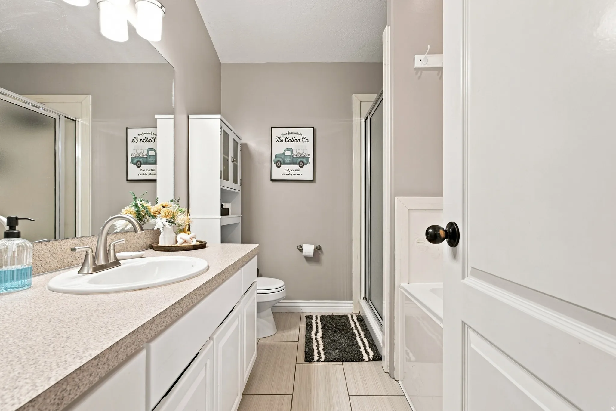 Bathroom featuring a vanity with an integrated sink, a large mirror, a built-in storage cabinet, a shower enclosure, and a tub