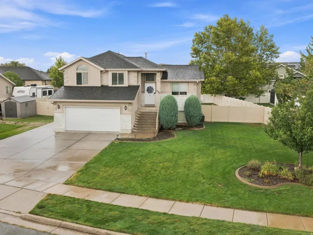 Two-story residence with a paved driveway, attached two-car garage, and a level lawn