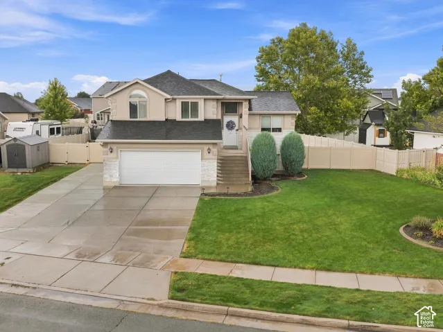 Split-level exterior featuring stucco and brick siding, a dual-gabled roof, an attached two-car garage, and a concrete driveway