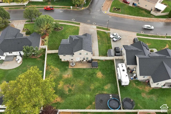 Expansive rear yard with a paved patio, mature trees, and fencing
