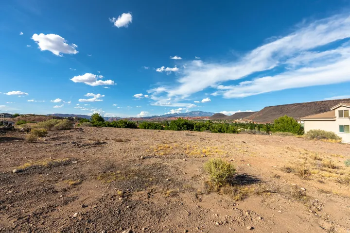 Expansive arid landscape with distant mountain ranges and scattered low-lying vegetation